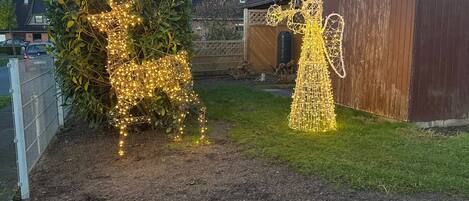A garden with a decorative tree and a lighted structure resembling a figure.