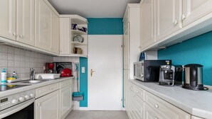 A kitchen with white cabinets, a microwave, a coffee maker, and a sink.