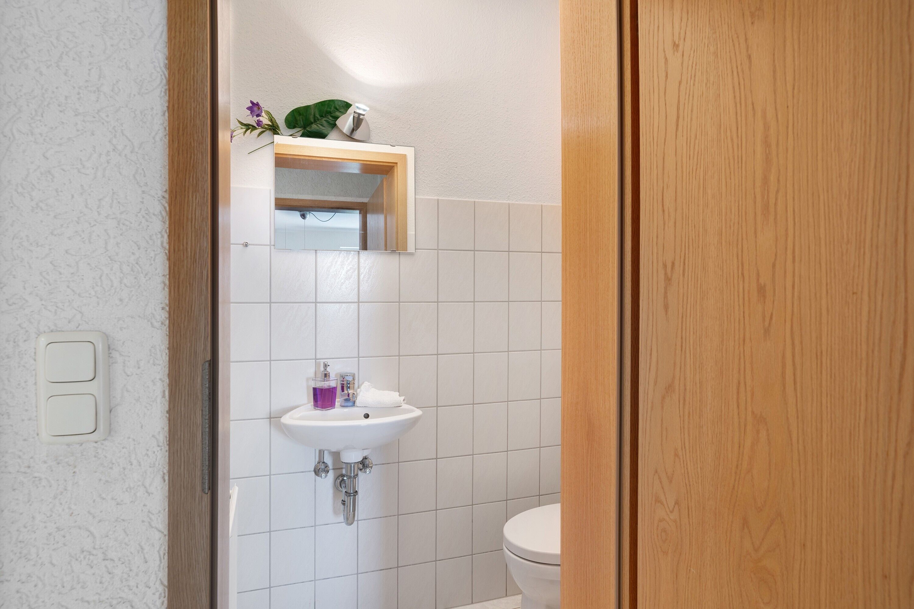 A bathroom with a white sink, mirror, and toilet.