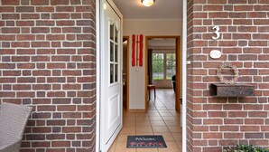 A brick-walled hallway with a door, a welcome mat, and a mailbox.