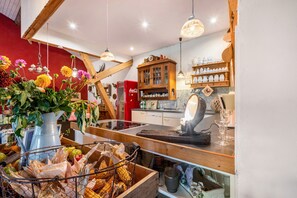 Une cuisine avec des poutres en bois, des suspensions fleuries et un vieux réfrigérateur Coca-Cola.