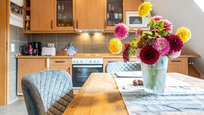 Una cocina con armarios de madera, una mesa de comedor con un florero y un microondas.
