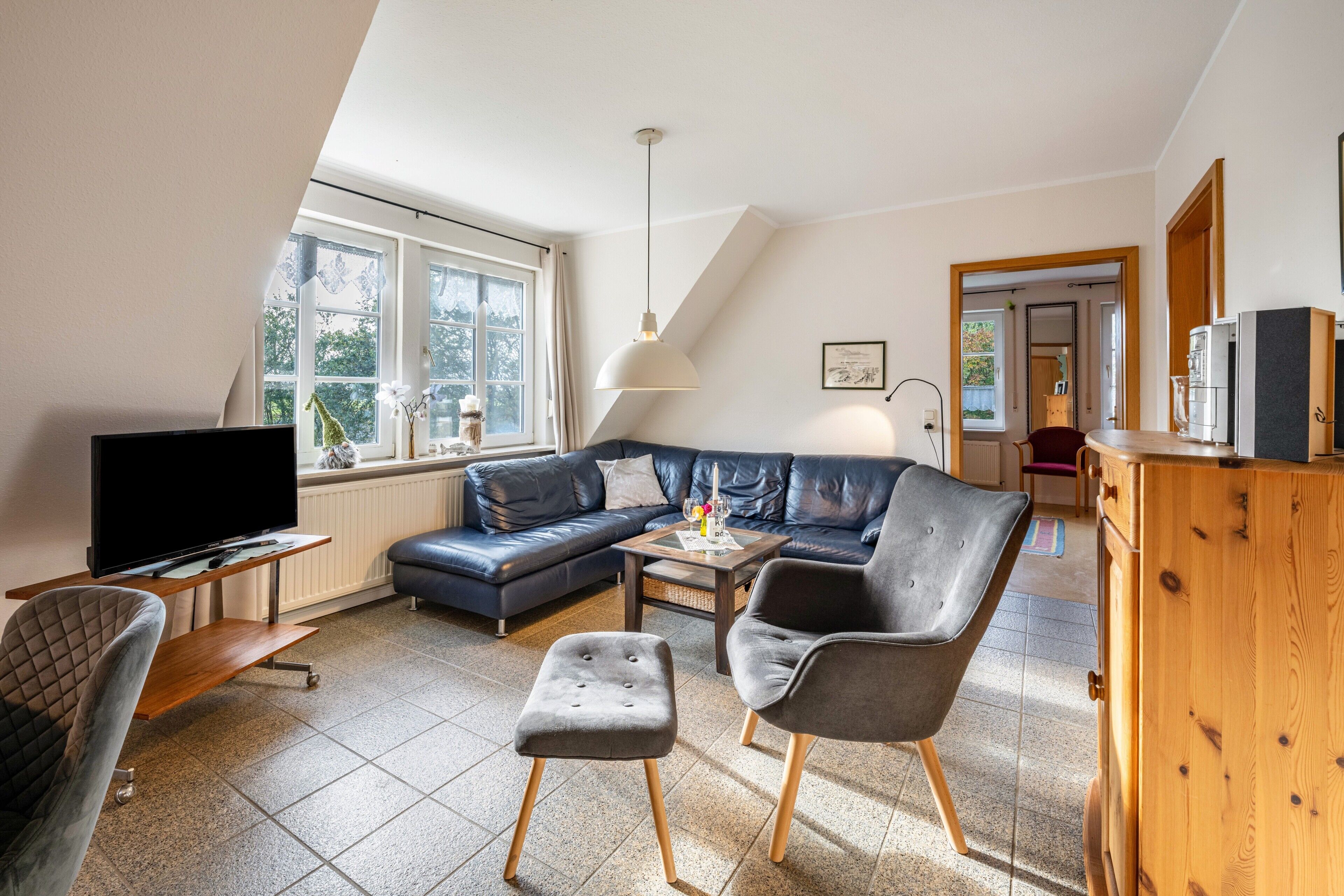 A living room with a TV, sofa, chairs, a coffee table, and a wooden cabinet.