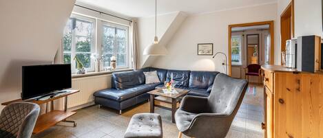 A living room with a TV, sofa, chairs, a coffee table, and a wooden cabinet.