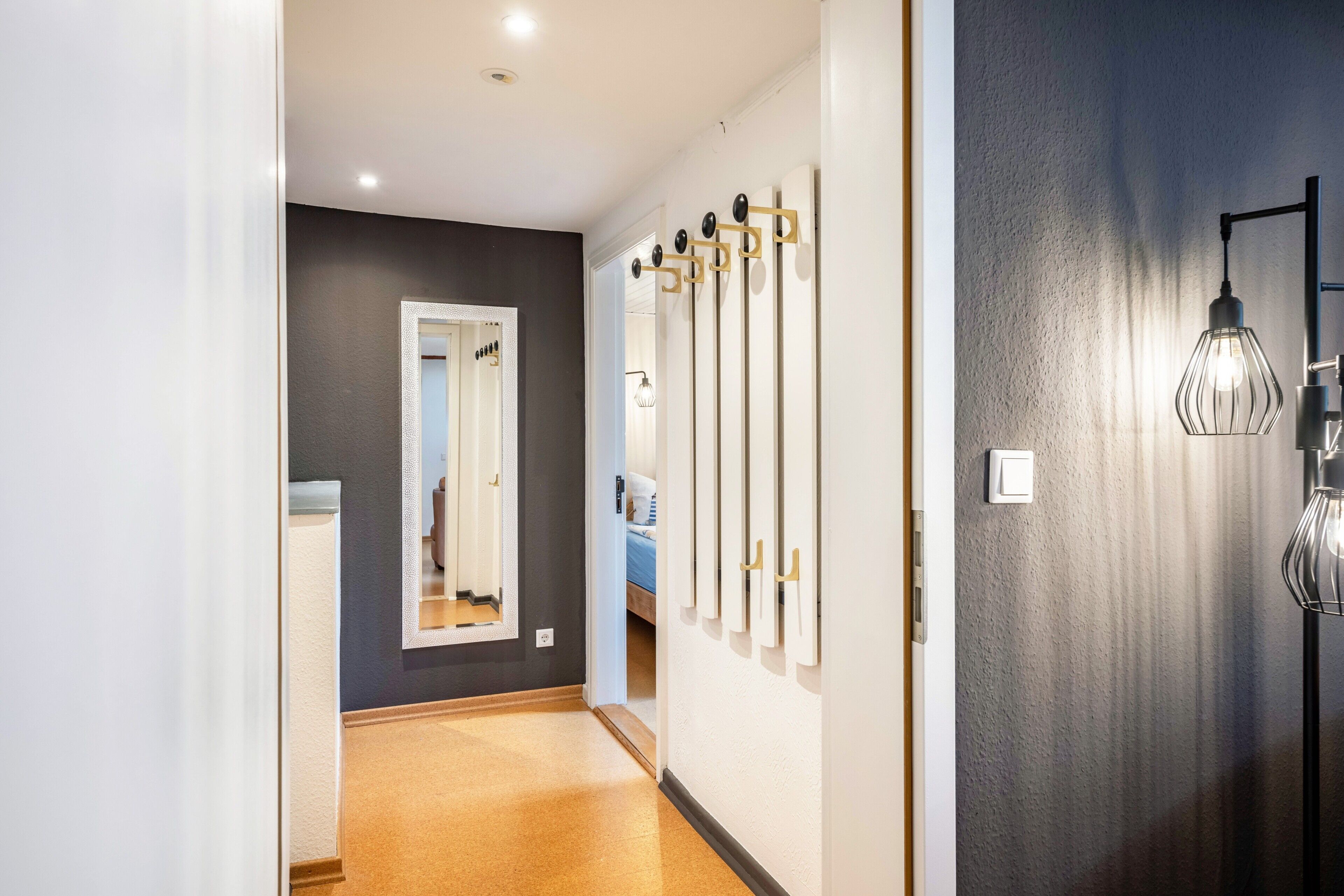 A hallway with a mirror, a coat rack, and a light fixture.