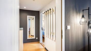 A hallway with a mirror, a coat rack, and a light fixture.