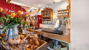 A kitchen with wooden beams, hanging flower baskets, and a vintage Coca-Cola refrigerator.