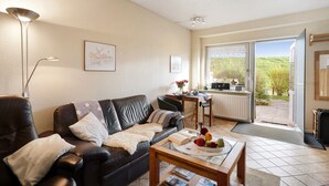 Een woonkamer met een bank, salontafel en een eethoek met tafel en stoelen.