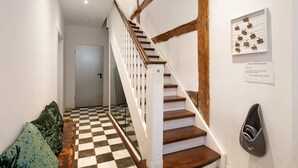 A staircase with wooden steps and white railings, a checkered floor, and a bench with cushions.