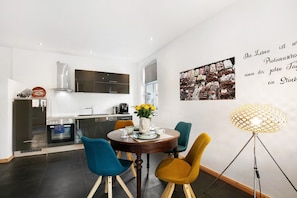 Een moderne keuken met een eethoek, een koffieapparaat en een muur met tekst en afbeelding.