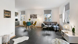 A modern living room with a sofa, coffee table, and dining area with chairs.