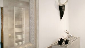 A wall-mounted skull with horns, a metal rack, and a silver deer head sculpture.