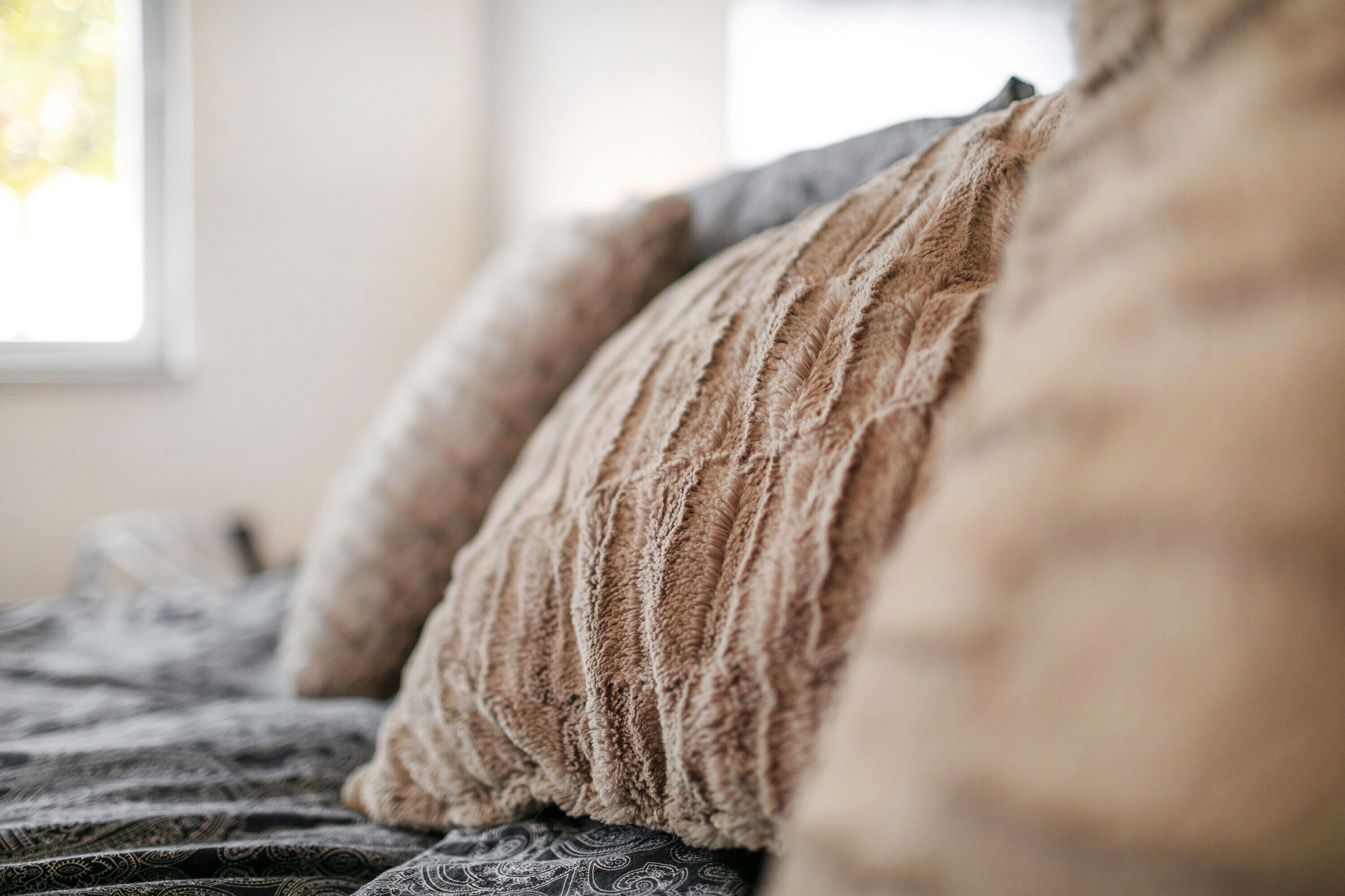 Een bed met beddengoed met een patroon en een raam op de achtergrond.