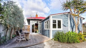 A house with a deck, a satellite dish, and a red roof. - The Blue House (Whanganui)