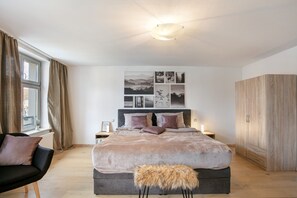 A bedroom with a bed, a chair, a wardrobe, and a window with curtains. - Apartment 'Klosterperle' with Wi-Fi (Neuruppin)