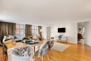 A modern living room with a sofa, a coffee table, a TV, and a dining area. - Apartment 'Klosterperle' with Wi-Fi (Neuruppin)