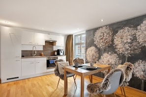 Una cocina moderna con armarios blancos, una mesa de comedor con sillas y un amplio mural floral en la pared.