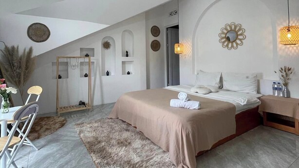 Un dormitorio moderno con una cama grande, una zona de comedor con sillas, una mesita pequeña y una pared decorativa con diseños circulares.