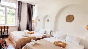 Una habitación de hotel con dos camas, un ventanal grande y un ventilador.
