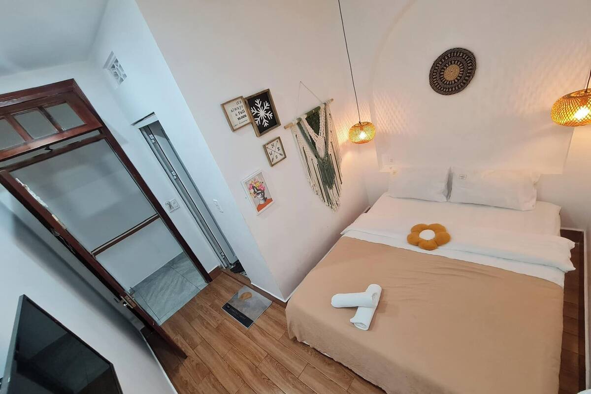 Een slaapkamer met een bed, een houten vloer, een deur en een wand met decoraties.