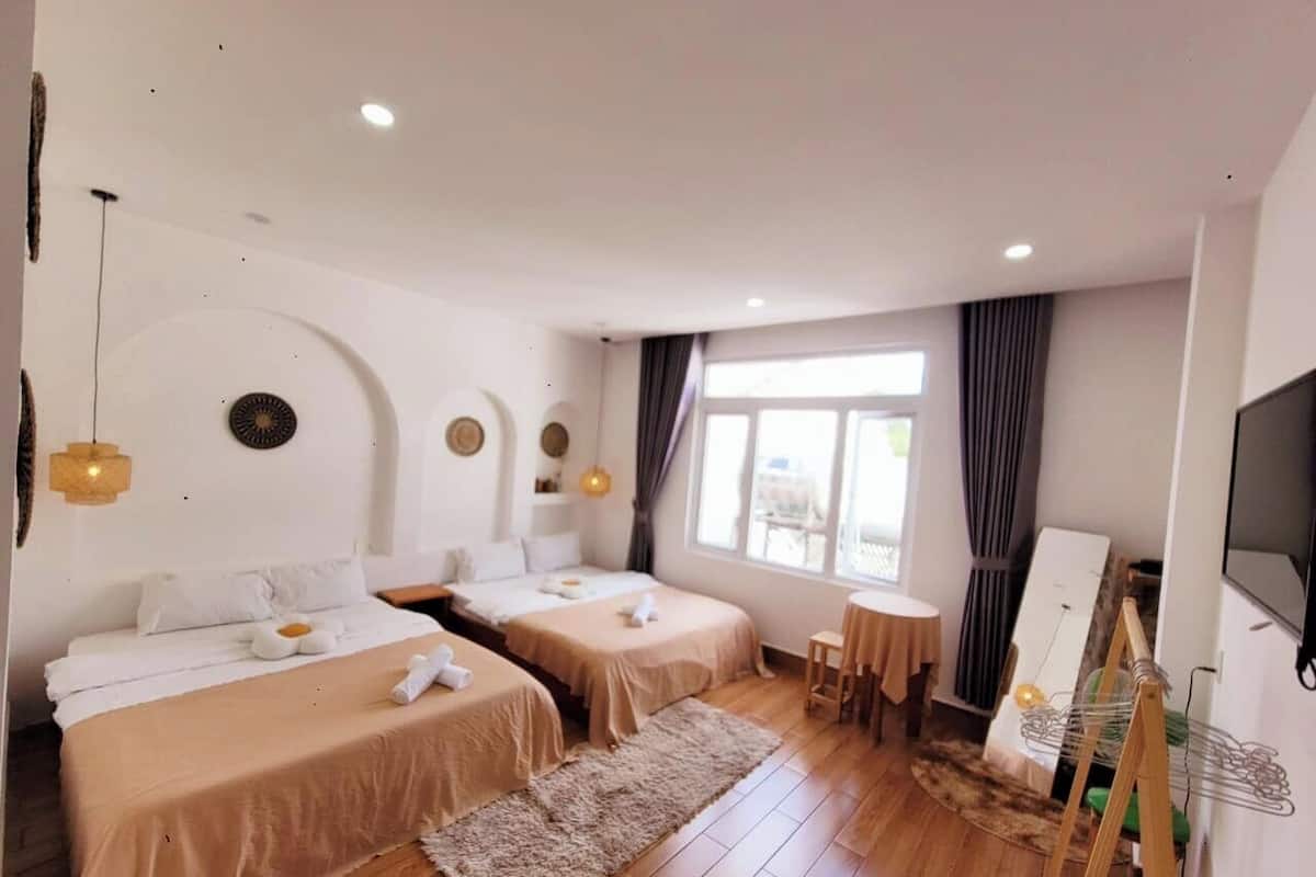 Een hotelkamer met twee bedden, een kleine tafel, een televisie en een schilderij aan de muur.