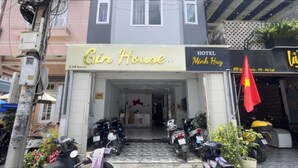 Un edificio con un letrero que dice 'Gin House' y un letrero que dice 'Hotel Minh Huyn'. Varias motocicletas están estacionadas adelante.