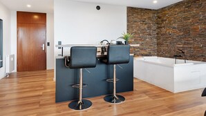A modern kitchen with two bar stools, a built-in island, and a stone accent wall.