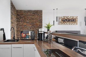 A modern kitchen with a stone wall, a coffee maker, a toaster, and a plant.