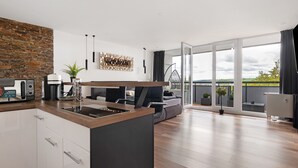 A modern kitchen with a stone accent wall, a dining area with a sofa, and a view of the outdoors through large sliding doors.