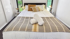 Una cama bien hecha con una colcha a rayas, dos almohadas y una toalla enrollada.