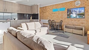Un espacio habitable moderno con cocina, sofá, mesa de comedor y un ventanal grande.