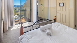 A bedroom with a bed, a view of the outdoors, and a balcony.