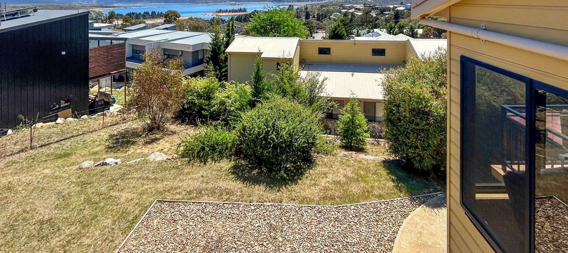 Un quartier résidentiel avec des maisons modernes, une vue sur un plan d’eau et un sentier de gravier.