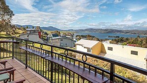 A balcony with a view of a lake and distant mountains.
