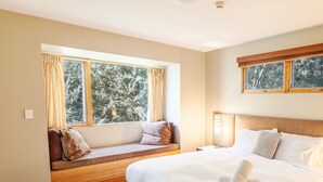 A bedroom with a large bed, a window seat, and a nightstand. - Escape 2 - Crackenback Ridge (Crackenback Ridge)