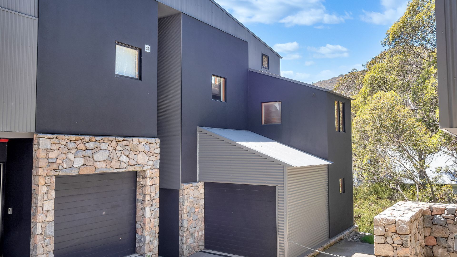 A modern two-story building with a stone facade and a garage door.