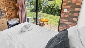 Hotellihuone, jossa on sänky, televisio, pieni pöytä ja tuoli.