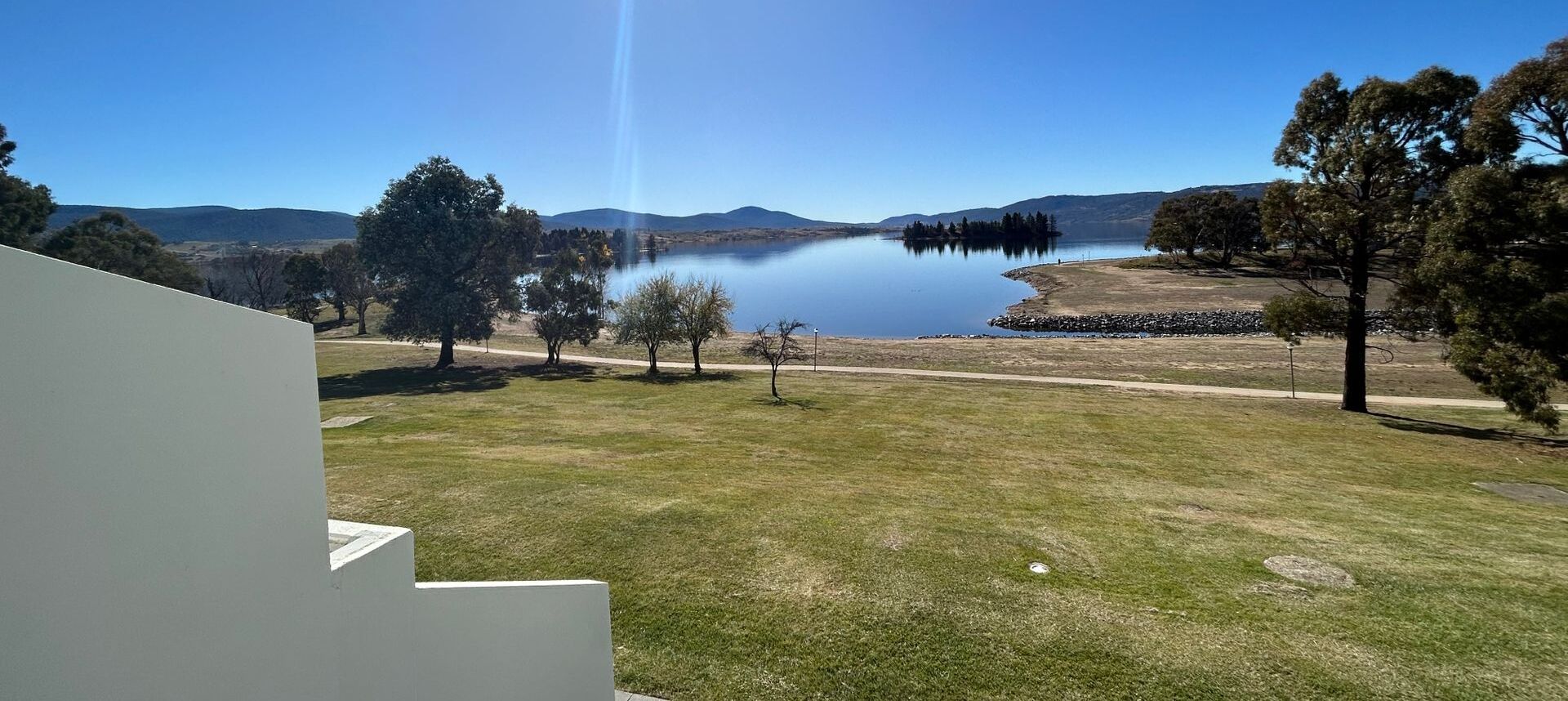 A view of a lake with surrounding trees and a clear sky.