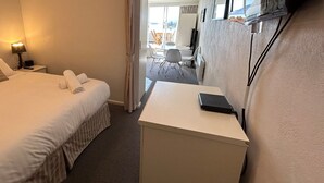 A hotel room with a bed, bedside table, lamp, and a desk with a laptop. - Horizons 317 studio right on the Lake (Jindabyne)