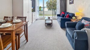 Un salon comprenant un canapé, une table basse et un coin repas avec des chaises et une table mise pour le repas.