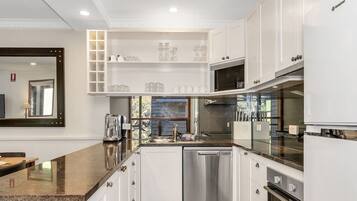 A modern kitchen with white cabinets, a granite countertop, and stainless steel appliances.