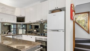 Una cocina moderna con armarios blancos, encimera de granito y electrodomésticos de acero inoxidable.