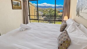 A bedroom with a large window offering a view of a mountainous landscape. - Alpine Mountain View 9 (Jindabyne)