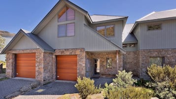 A modern two-story house with a stone facade, two garage doors, and a small porch.