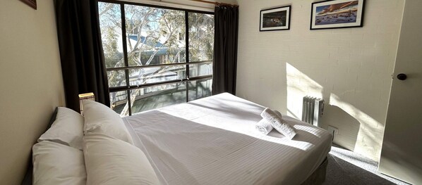 Enjoy a restful stay in this serene room with a large bed and a window offering a view of the surrounding landscape.