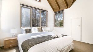 A bedroom with a large bed, two bedside tables, a window, and a door.