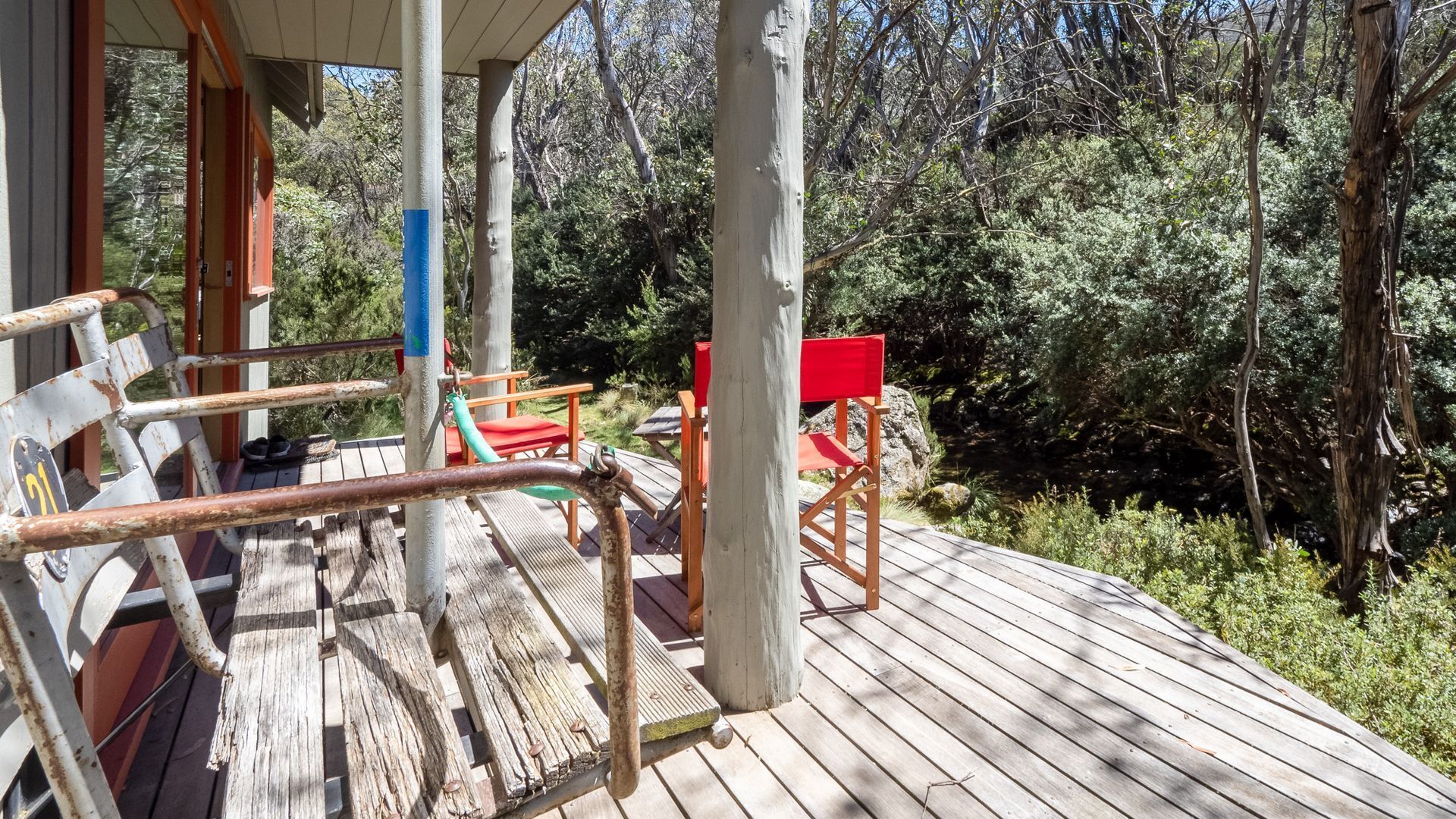 Une terrasse en bois avec des sièges extérieurs et une forêt luxuriante en arrière-plan.