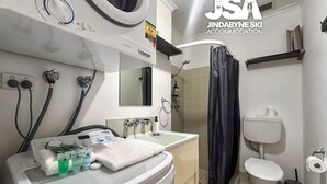 A bathroom with a sink, mirror, towel, and shower curtain.