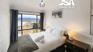 A hotel room with a large bed, a view of the countryside, and a framed picture on the wall.
