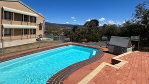 Ein rechteckiger Swimmingpool mit Ziegelkanten, umgeben von einer Ziegelterrasse.